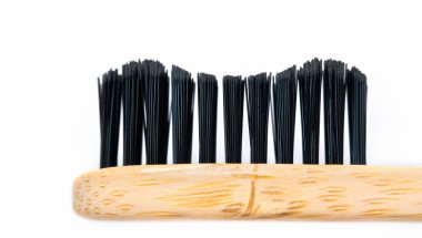 Siyah tüylü bambu diş fırçası beyaz arka planda izole edilmiş. Makro çekim, ağız temizliği konsepti.