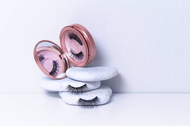 Beyaz arka planda pembe ayna kutusunda manyetik sahte kirpikler. Ev kirpik uzatma, kozmetoloji aracı konsept, güzellik tedavisi, fiziksel görünümün iyileştirilmesi