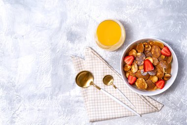 Çilekli küçük krep gevreği ve beton zeminde portakal suyu bardağı. Moda kahvaltı, Amerikan yemeği, mesaj için yer.