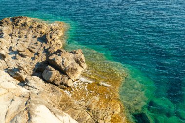 İtalya, Toskana, Baratti 'deki Tirrenia Denizi' nin Rocky plajı ve turkuaz suyu. Cliff Buca delle Fate. Turizm merkezi.