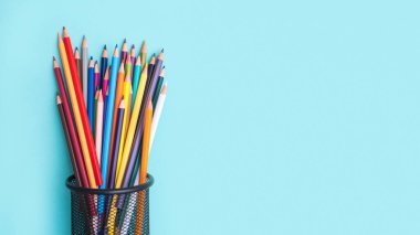 Yeşil arka planda çok renkli kalemlerin palet seti. Mesaj atmak için yer var, okula dönmek için. Çizim ve çizim hobisi. Kırtasiye malzemeleri mağazası