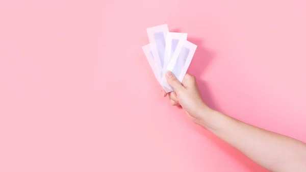 Pembe arka planda mavi balmumu çizgileri olan bir kadın. Kılları ayıklamak. Minimalizm. Üst Manzara. Vücut hijyeni, spa prosedürleri afişi.