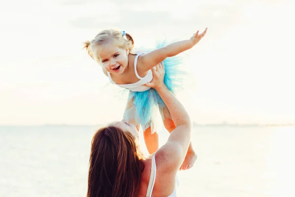 Mom with a little daughter at the sea laughing