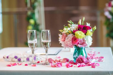 Düğün töreni için iki şampanya bardağı ve bir buket taze çiçek.