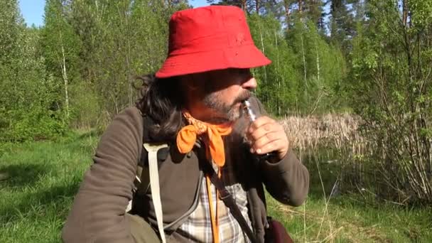 Oudere Man uitademen rook uit een vaporizer in de natuur van bos moeras in ochtend — Stockvideo