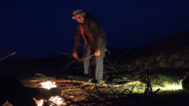 成熟した男は休憩し 夜の山の中のたき火用の乾燥枝をカットします アクティブな人の旅行者 — ストック動画