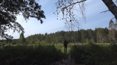 Olgun Erkek seyahat etmek sırt çantası ile ahşap eski yıkılan köprü vahşi orman akışında üzerinde yavaşça yürüyor. Etkinlikler yaz gününde