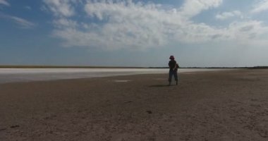 Olgun kadın gezgin bir sırt çantası ile öğlen güneşin kavurucu altında beyaz tuzlu göl çamurlu yağlı alt yürür