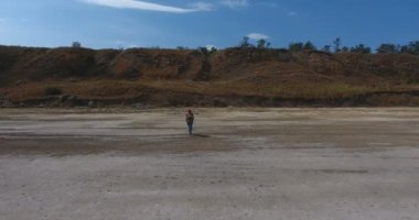 Olgun kadın gezgin bir sırt çantası ile öğlen güneşin kavurucu altında beyaz tuzlu göl çamurlu yağlı alt yürür