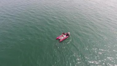 Hava görüntüsü. İki dalış dalgıcı, açık denizde, denizin içinde, kırmızı bottan suya dalıyor.