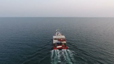 Açık denizdeki kırmızı katamaranın üst görüntüsü, sakin ve pürüzsüz suda son sürat gider.