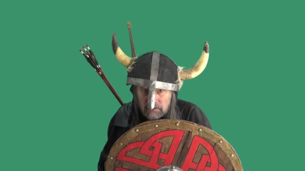 Portrét agresivního rozzlobeného staršího Vikinga v helmě s rohy, vyhrožujícího sekerou a křičícího nadávky. Muž na zeleném pozadí