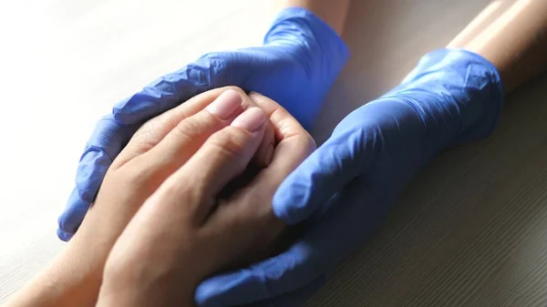 Doktor hastanın güvenini tazeler. Covid-19. Tıbbi eldivenli eller. Zor zamanlardaki bir hasta için doktor desteği. Çaresiz adam. Takım çalışması. Hastalıktan kurtulmanın bir yolunu bul. Yakın plan.