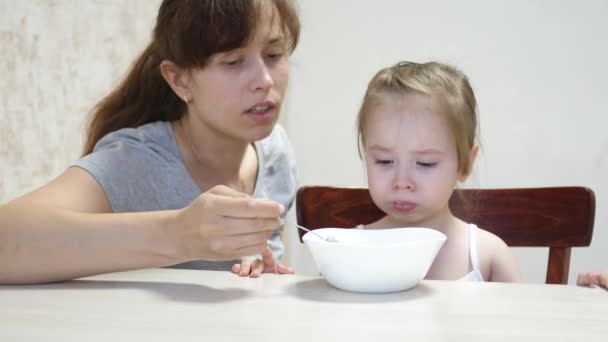 Mama füttert das Baby mit einem Löffel. Milchfrühstück für ein gesundes Baby. Mutterschafts- und Mutterschaftsurlaub Teamarbeit — Stockvideo