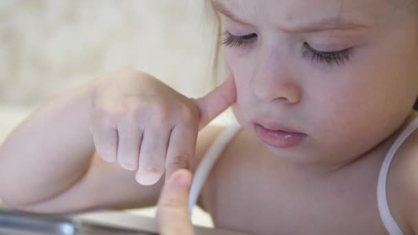 छोटी लड़की एक स्मार्टफोन में खेलती है। बच्चा दूर से फोन एप्लिकेशन में सीखता है। इंटरनेट पर प्रीस्कूलर — स्टॉक वीडियो