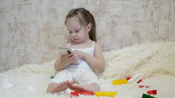 Kind spielt im Zimmer mit dem Smartphone. Fernunterricht von Vorschulkindern online — Stockvideo