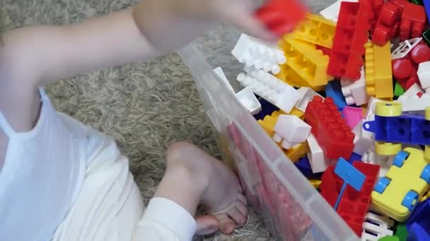 Un enfant ramasse un jouet dans une boîte. Jeu de concepteur d'enfants pour améliorer les capacités motrices, le développement du cerveau et la pensée. Gros plan — Video