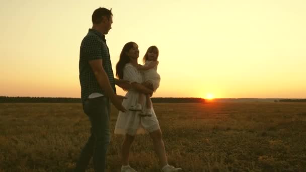 Os pais com uma criança pequena brincam fora da cidade ao pôr-do-sol. Mãe pai e filho riem juntos. Fins de semana com família. Trabalho em equipa — Vídeo de Stock