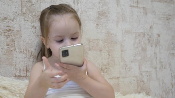 Un niño pequeño está hablando por teléfono vía videollamada. Kid se comunica de forma remota a través de una aplicación móvil. Educación preescolar mediante Internet. Primer plano — Vídeo de stock