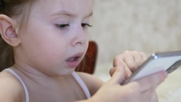 Kind spielt im Zimmer mit dem Smartphone. Fernunterricht von Vorschulkindern online — Stockvideo