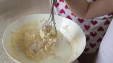 Anne bir çocuğa hamur pişirmeyi öğretiyor. Anne ve çocuk çırpılmış bir çırpıda bir parça un ve sütle dövülmüş. Evde ailenle yemek pişirmek. Takım çalışması.