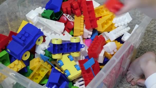 The kid collects toys in boxes. Designer bricks for a child. Educational game for a little baby. Close-up — Stock Video