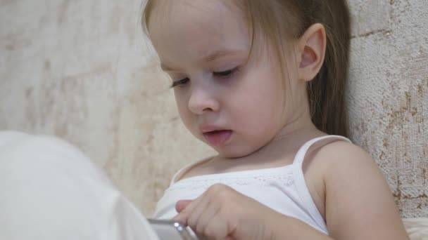 Dziecko bawi się w smartfonie w pokoju. Kształcenie na odległość przedszkolaków online — Wideo stockowe