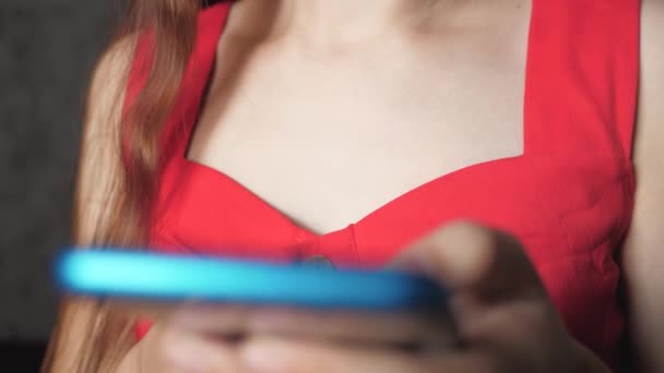 Het meisje doet winkelen via de internet-applicatie in de smartphone. Telefoon op de achtergrond van een vrouwelijke borst. Zakelijke en online lessen op afstand. Close-up — Stockvideo