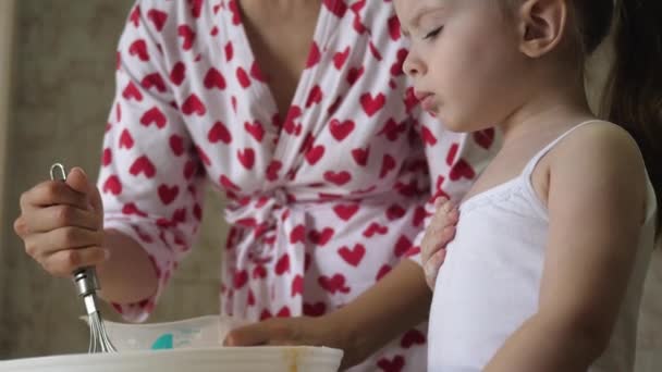Mor lærer et barn at lave mad dej. Mor og datter omrøres med et piskeris en masse mel. Madlavning derhjemme med familien. Teamwork – Stock-video