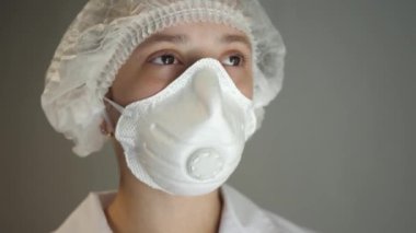 Surat maskesi takan doktor ve gülümseyen şapkalı doktor. Beyaz önlüklü bir sağlık görevlisi. COVID-19. Salgın. Yakın plan.
