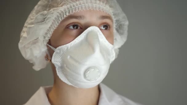 Doutor em máscara respiradora para rosto e chapéu médico sorrindo. Um médico de casaco branco. COVID-19. Pandemia. Close-up — Vídeo de Stock