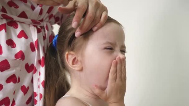 Mamma hugger en hårnål gäspar barn på håret. Grabben med föräldern. Familjemorgon. För att städa upp. Föräldern gör dottern till frisyr. Närbild — Stockvideo