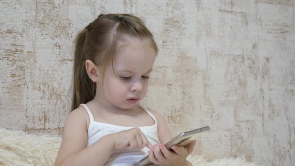 Un niño pequeño está hablando por teléfono vía videollamada. Kid se comunica de forma remota a través de una aplicación móvil. Educación preescolar mediante Internet. Primer plano — Vídeo de stock