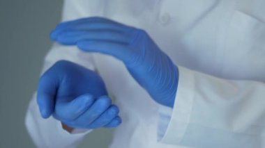 Doktor sabahlık ve eldiven giymiş, başarıyı alkışlayarak kutluyor ve ellerini çırpıyor. Covid-19. Salgın. Yakın plan.