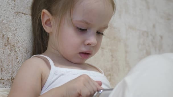 Barnet leker i smarttelefonen i rummet. Distansundervisning för förskolebarn online — Stockvideo
