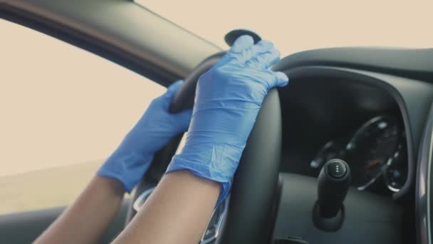 Das Mädchen dreht mit medizinisch-blauen Handschuhen am Lenkrad des Autos. Schutz gegen das Covid-19-Virus. Pandemie. Nahaufnahme — Stockvideo