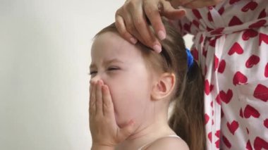 Annem bebek saçını tarar ve lastiğin üzerinde at kuyruğu şeklinde toplar. Aile sabahı. İşleri yoluna koymak. Ebeveyn, kızı saç stili yapar. Yakın plan.