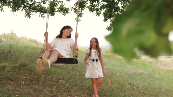 Heureux enfant secoue mère sur une balançoire. Un enfant avec sa mère pour une promenade se promène dans le parc un jour de congé. Travail d'équipe. Concept de famille heureuse — Video