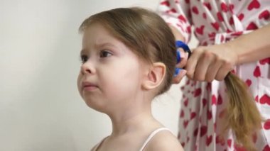 Bebeklerin saçını annem yapıyor. Çocukların saçı elastik bir bantla at kuyruğu şeklinde bağlanmış. Uzun saçlı küçük kız. Yakın plan.