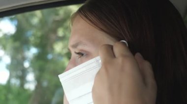 Güzel bir kız arabayla gider ve maske takar. Böylece etrafındaki insanlara Covid-19 bulaştırmaz. Enfeksiyon ve gribe karşı koruma. Yakın plan.
