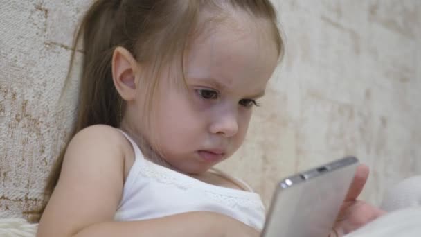 Grabben spelar i smarttelefonen i rummet. Distansundervisning för förskolebarn online — Stockvideo
