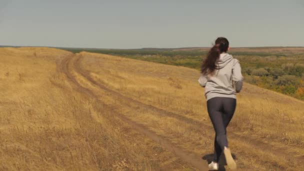 Sağlıklı güzel kız spor yapıyor, kırsalda koşuyor. Antrenman koşusu. Özgür genç bir kadın yazın parkta koşar. Koşucu kız temiz hava alır. — Stok video