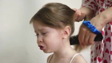 Bebeklerin saçını annem yapıyor. Çocukların saçı elastik bir bantla at kuyruğu şeklinde bağlanmış. Uzun saçlı küçük kız. Yakın plan.