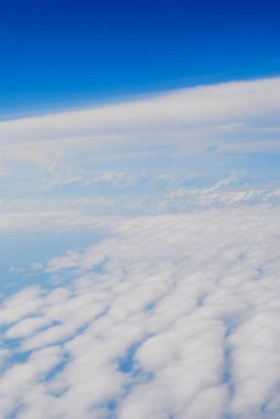 Bulutlu mavi gökyüzünün havadan görüntüsü. Uçak penceresinden bulutlar ve gökyüzü