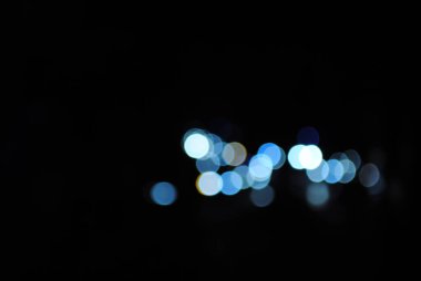 Büyük bir şehrin caddesinde gece vakti Bokeh trafik ışığı. Bokeh efektli soğuk mavi ve mor arkaplan ile bulanık sıcak ışıkların soyut arkaplanı