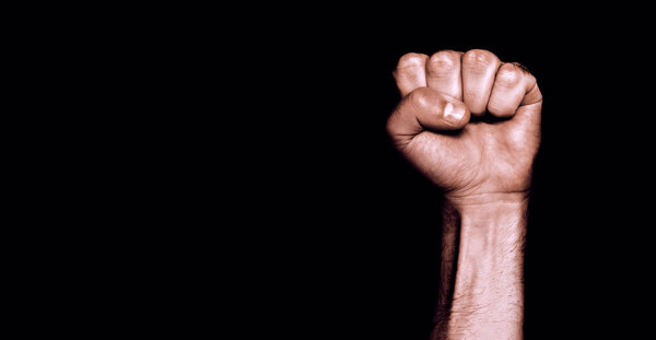 Male black fist on a black background. Aggressiveness, masculinity, the concept of challenge.