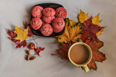 Siyah bir tabakta yabanmersinli kurabiyeler, renkli sonbahar akçaağaç yaprakları ve gri arka planda bir fincan kahve. Sonbahar konsepti. Üst görünüm.