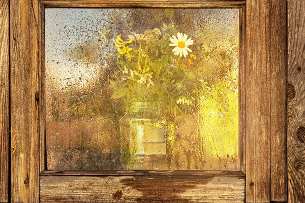 Vase with a bouquet of wild flowers through the wet window glass at sunset. Autumn season. — Stock Image Vase Bouquet Wild Flowers Wet Window Glass Sunset Autumn Season Stock Photo