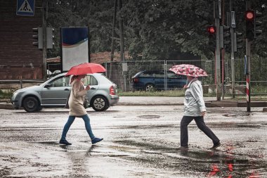 İki yayalar karşıdan karşıya geçerken bir yağmurlu bahar gününde Tallinn, Estonya sermaye. Yağmur yağıyor ve şemsiyeler de ihtiyaç vardır.