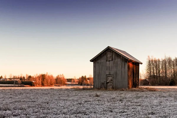 寒い冬の朝日の出色美しくフィンランド北部にあるフィールドです 小さな納屋ハウスは冷ややかなフィールドに単独で立っています — ストック写真